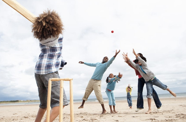 Families playing cricket on a beach